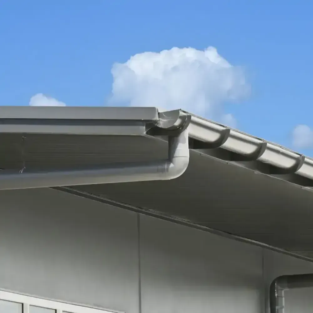 Gray building with matching gutters and a clear blue sky with fluffy white clouds in the background.