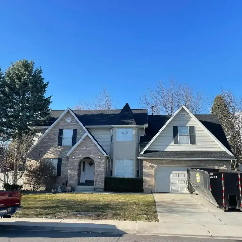 Two-story house with a driveway. A moving truck is parked in front of the garage. Clear blue sky.