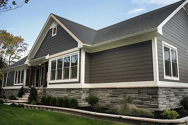 House with gray siding and stone base, white trim, and a dark roof.