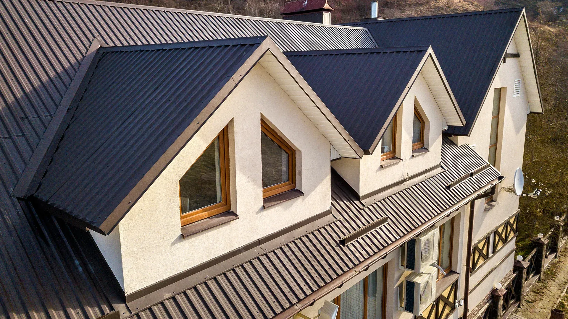 Construction workers installing roofing on a wooden house frame outdoors.