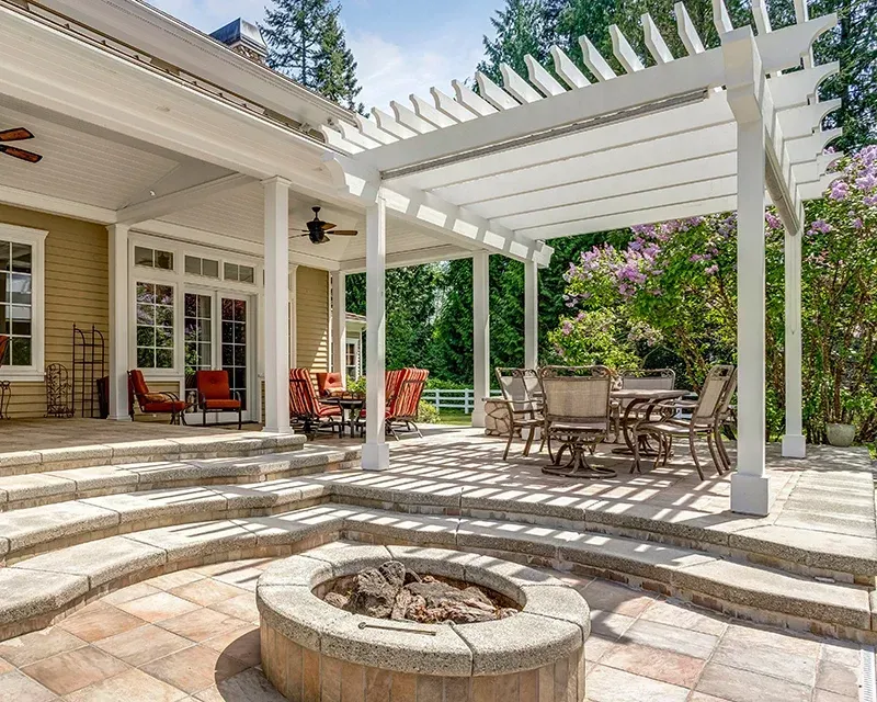 Patio with pergola, outdoor furniture, fire pit, stone steps, and house.