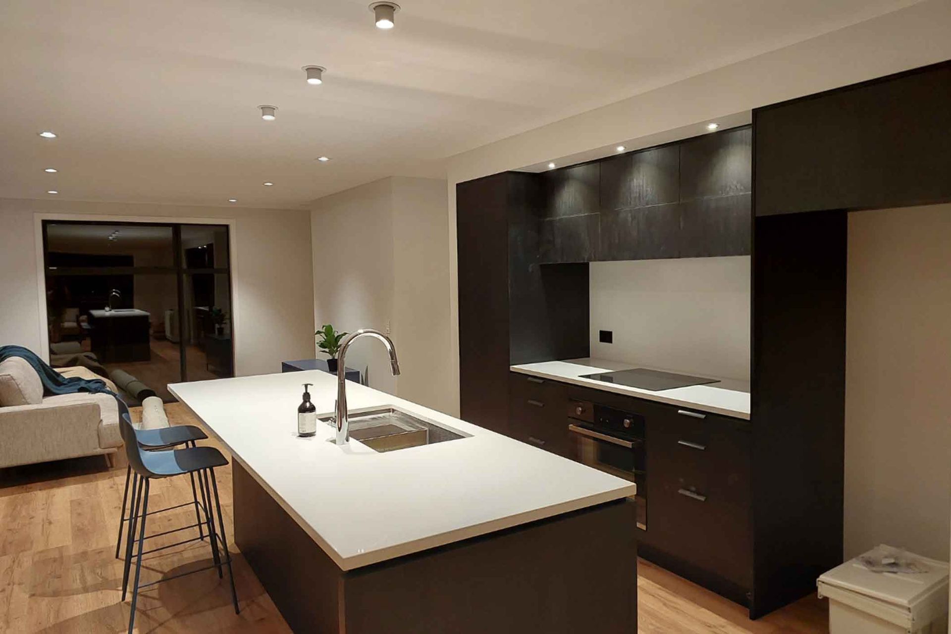 Modern kitchen with island, dark cabinets, white countertop, and bar stools.