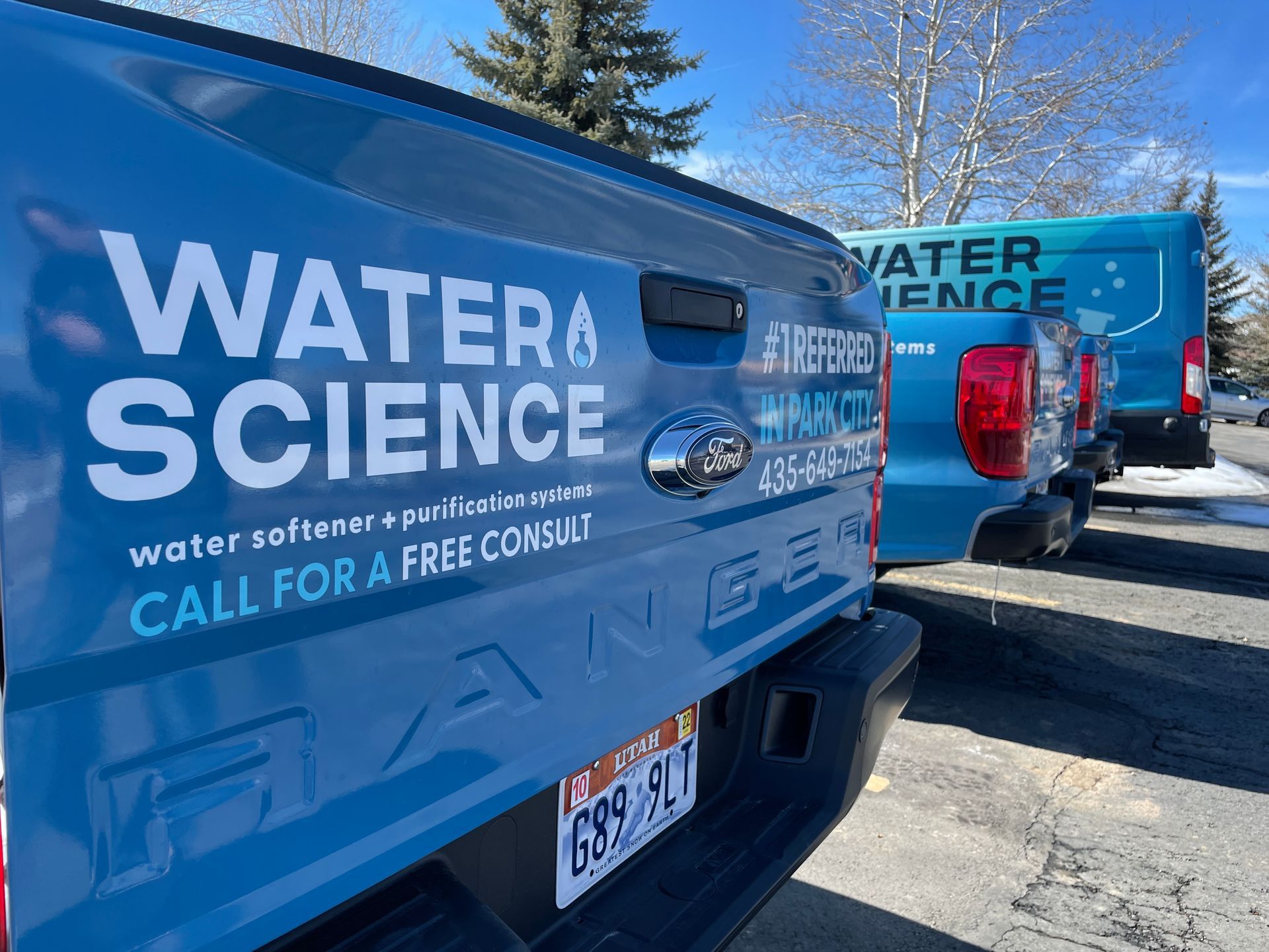 A row of water science trucks are parked in a parking lot.