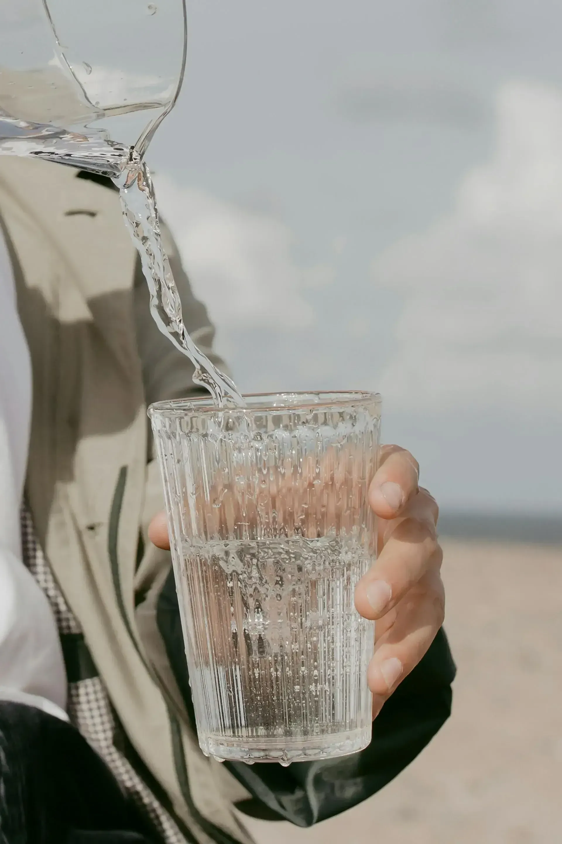 person pouring water from pitcher to glass