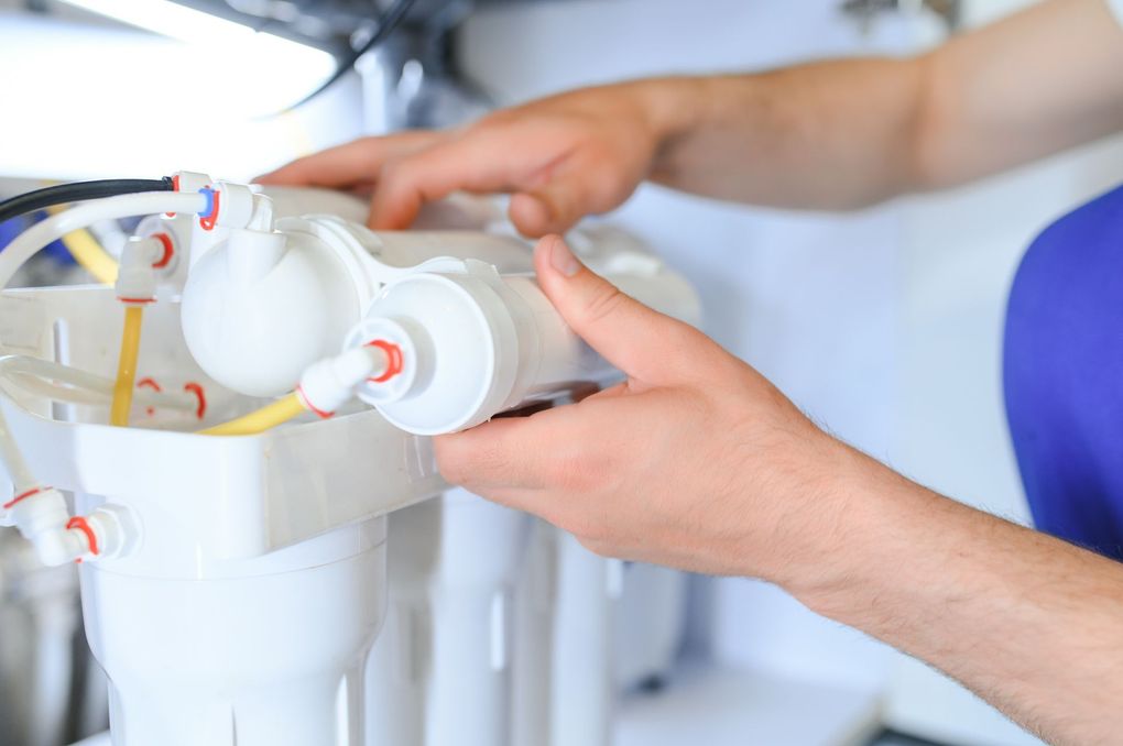 A person is fixing a water filter in a kitchen.