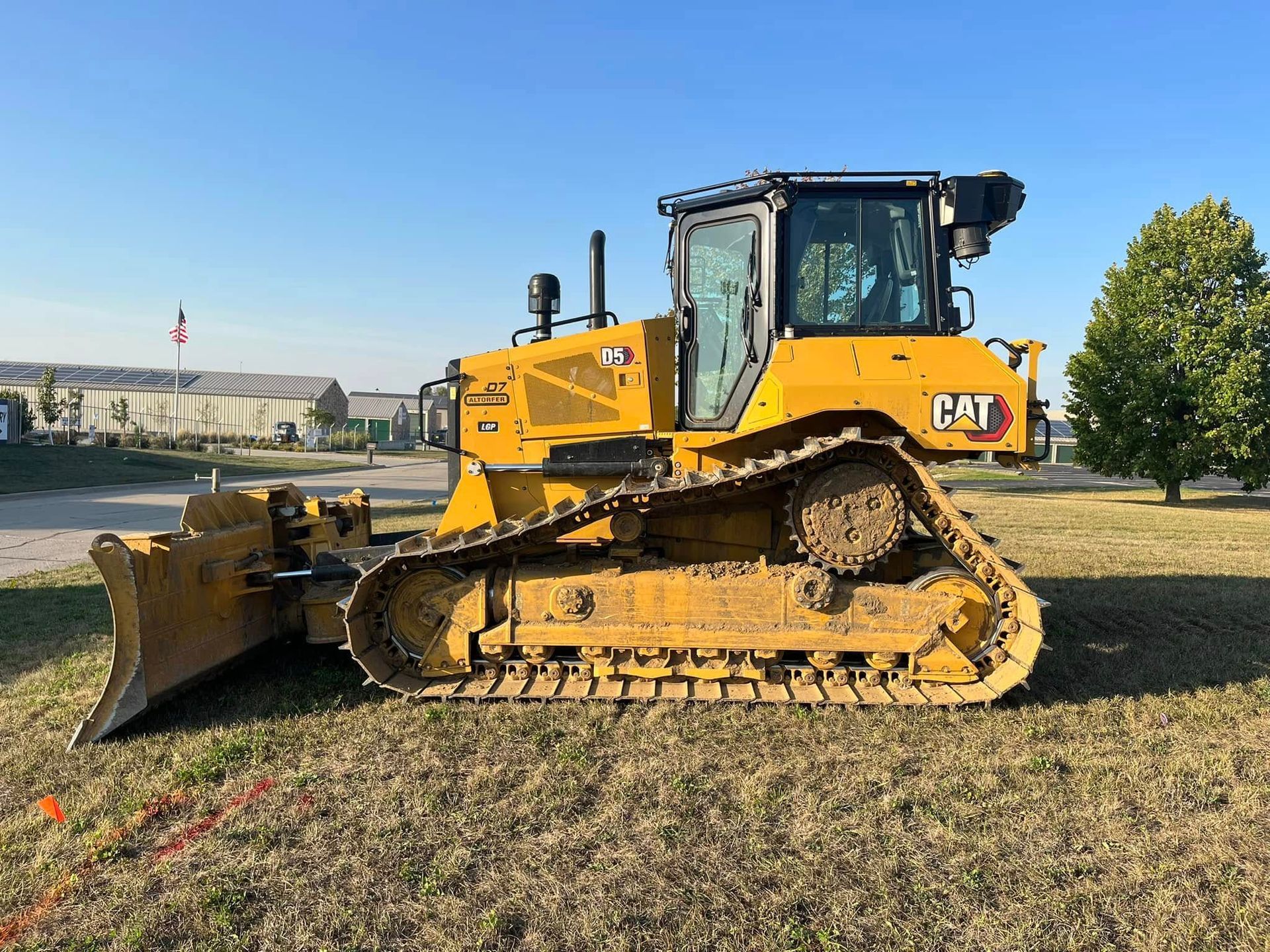 A yellow bulldozer is parked in a grassy field.