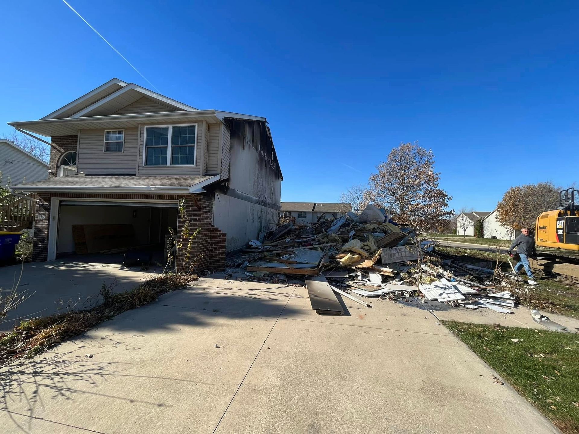 A house is being demolished with a bulldozer in the background.