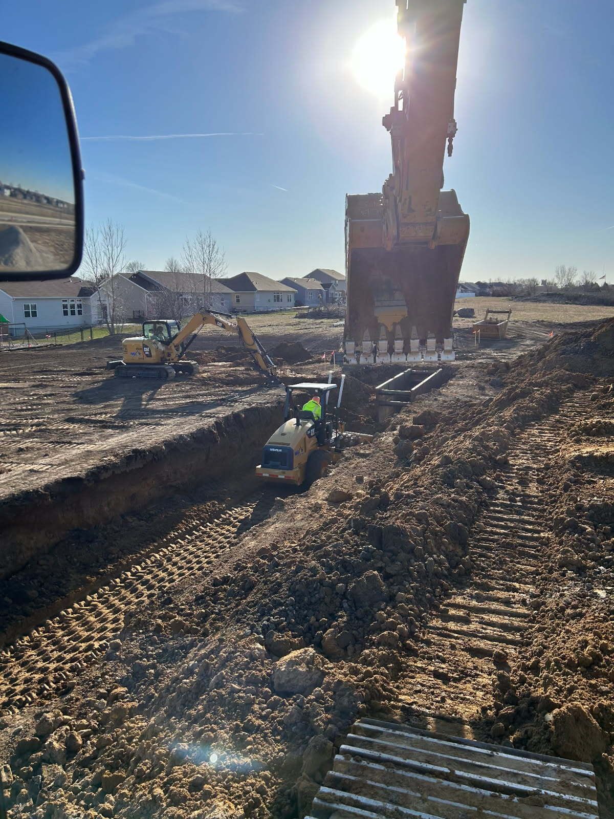 Construction site with excavators digging trenches on a sunny day.