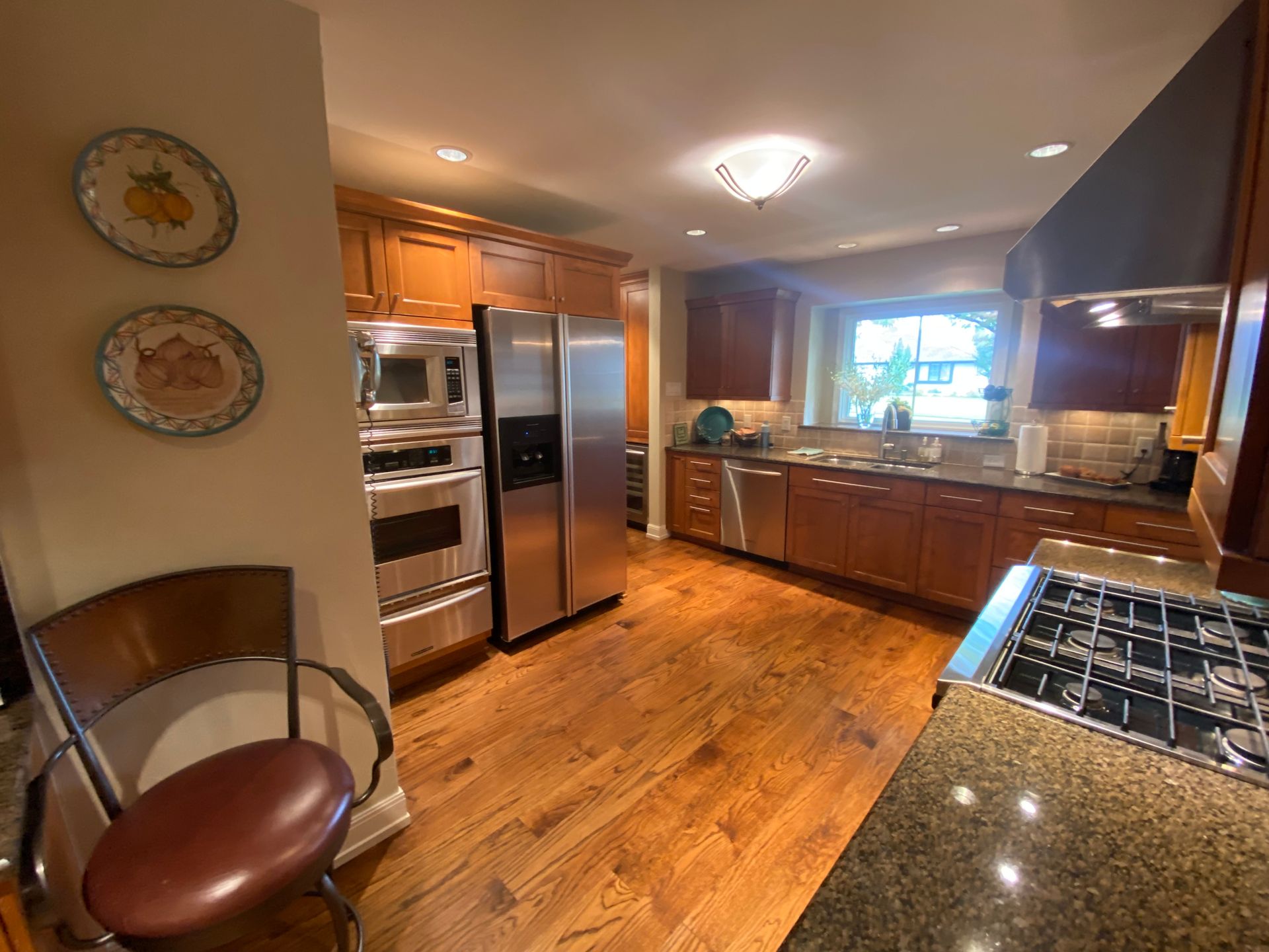 A dining room with a wooden table, patterned chairs, a chandelier, a wall mirror, and a grandfather clock.