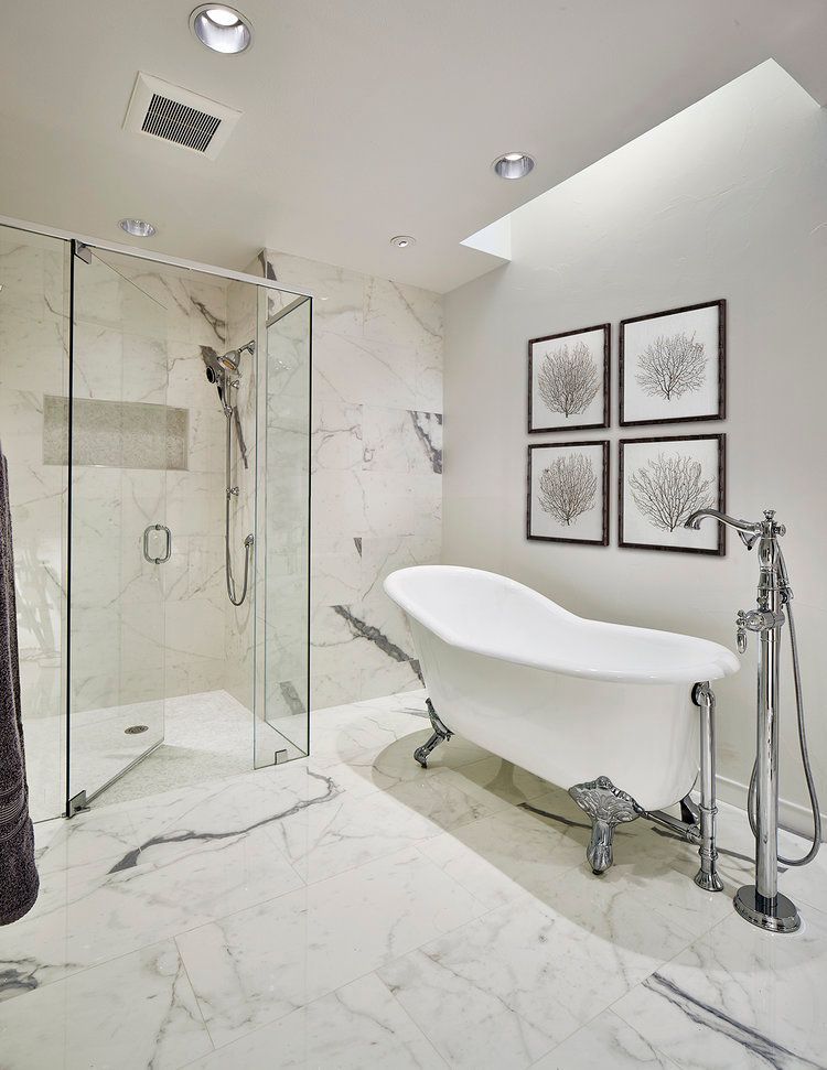 Elegant bathroom with a clawfoot bathtub, marble floors, glass shower, and framed art.