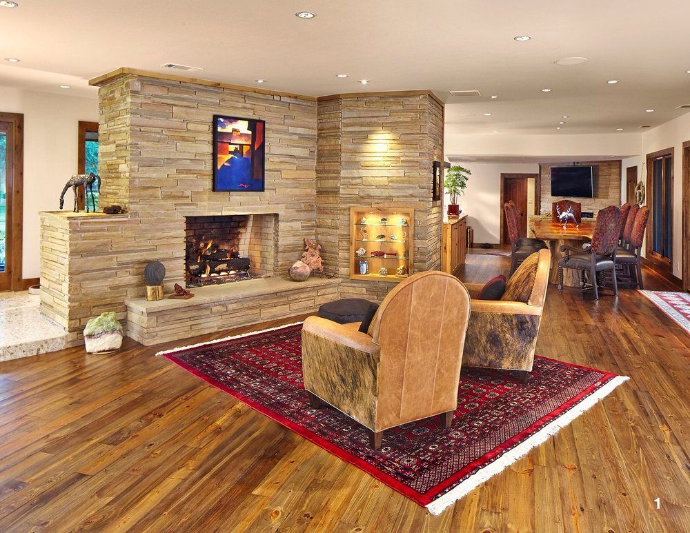 Cozy living room with stone fireplace, wooden floor, area rug, and armchairs.