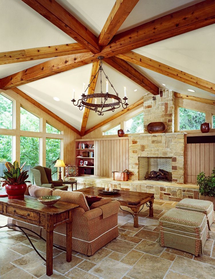 Living room with vaulted ceiling, exposed beams, stone fireplace, and rustic furniture.