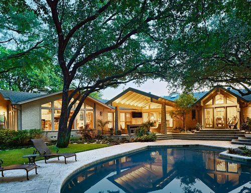 Poolside view of a modern house with a pool, patio furniture, and large tree.