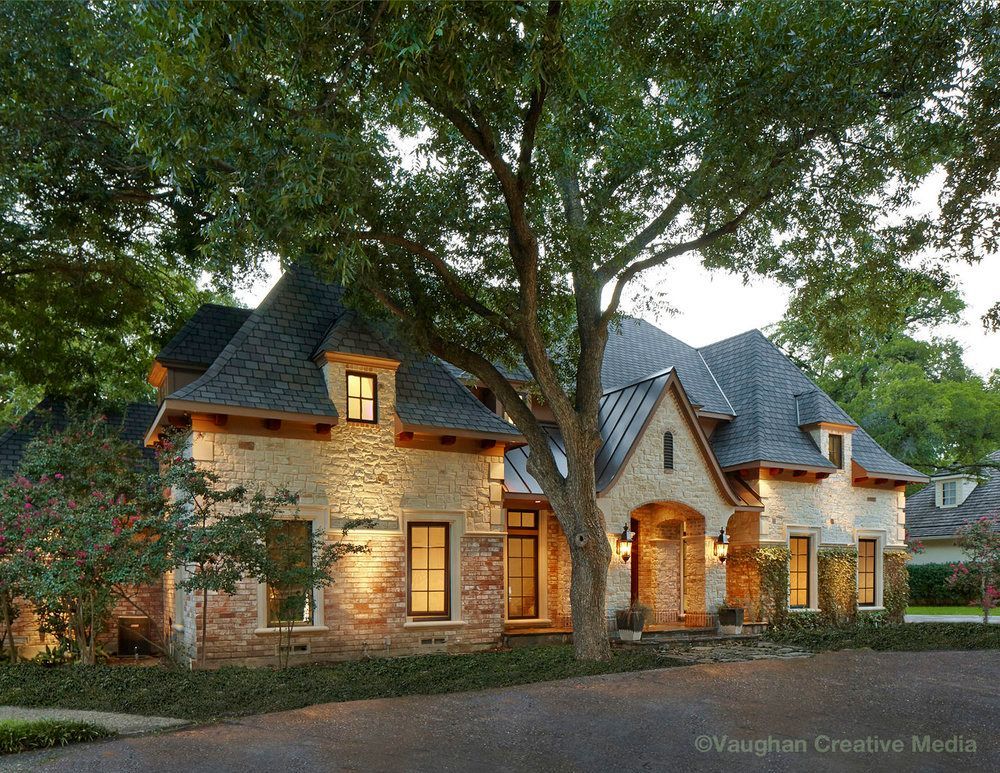 Stone and brick house with dark roof and large tree in front. Evening lighting. Richardson exterior renovation.