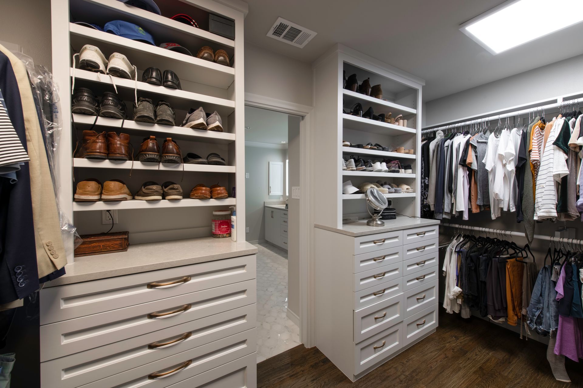 Walk-in closet with white shelves and drawers for shoes and clothing. Open space.