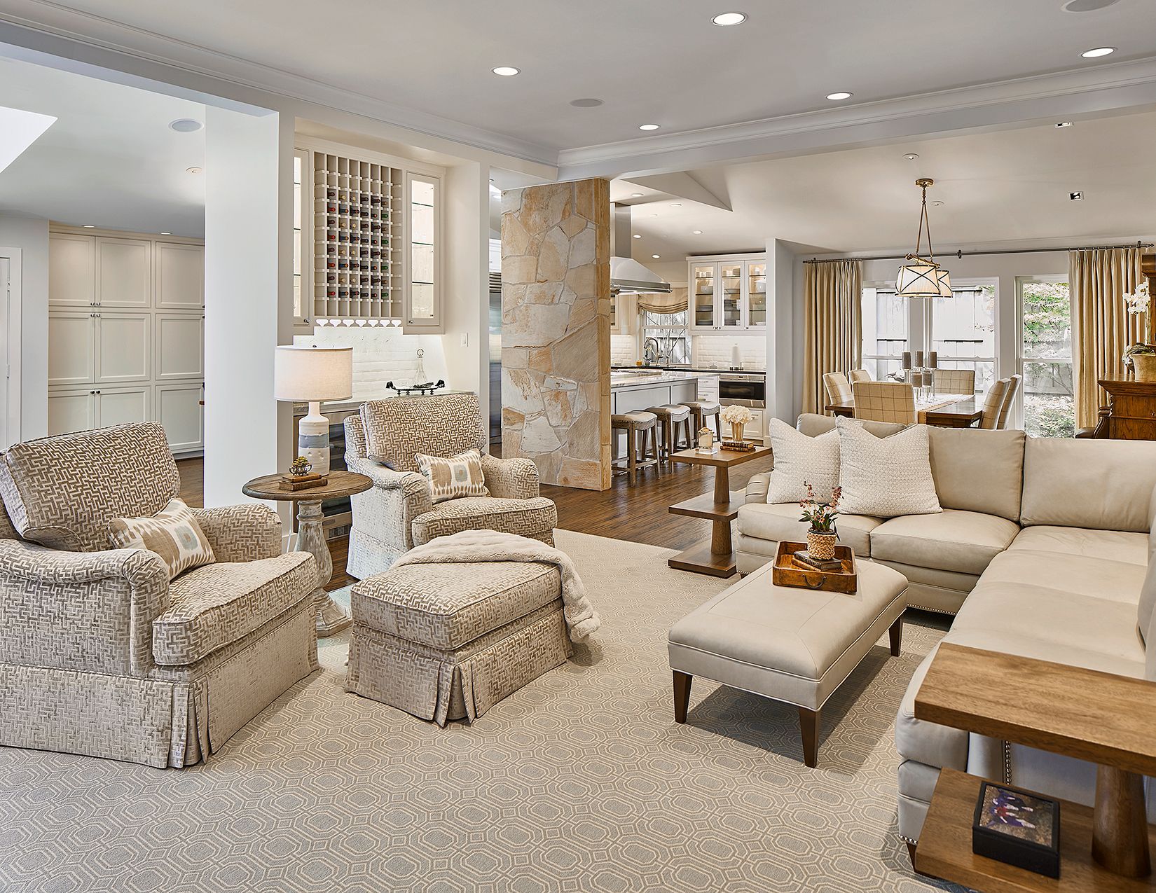 Spacious, light-filled living room with neutral colors, and an open layout connecting to a kitchen and dining area.