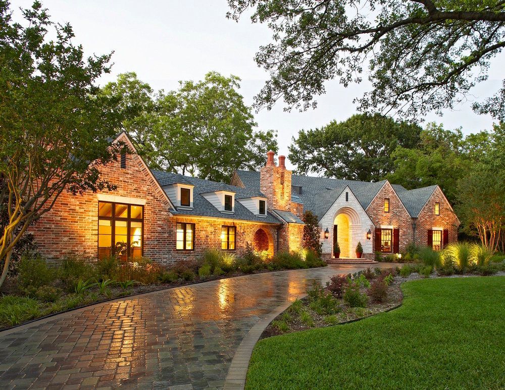 Brick house with illuminated driveway and landscaping.