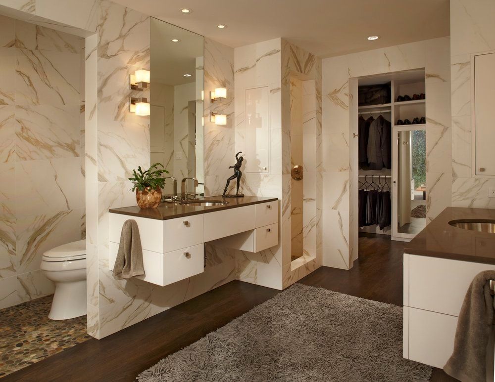 Modern bathroom with marble walls, floating vanity, and walk-in closet.