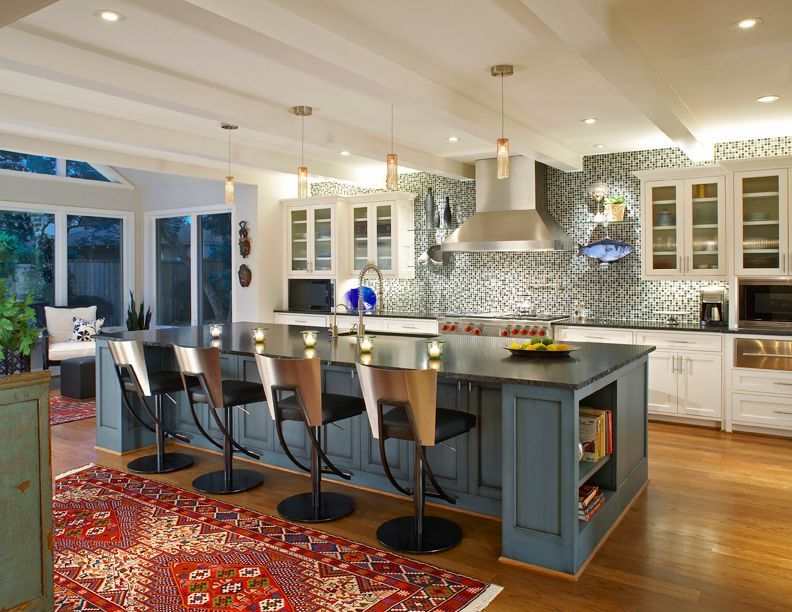 Modern kitchen with blue island and seating, white cabinets, and patterned backsplash.