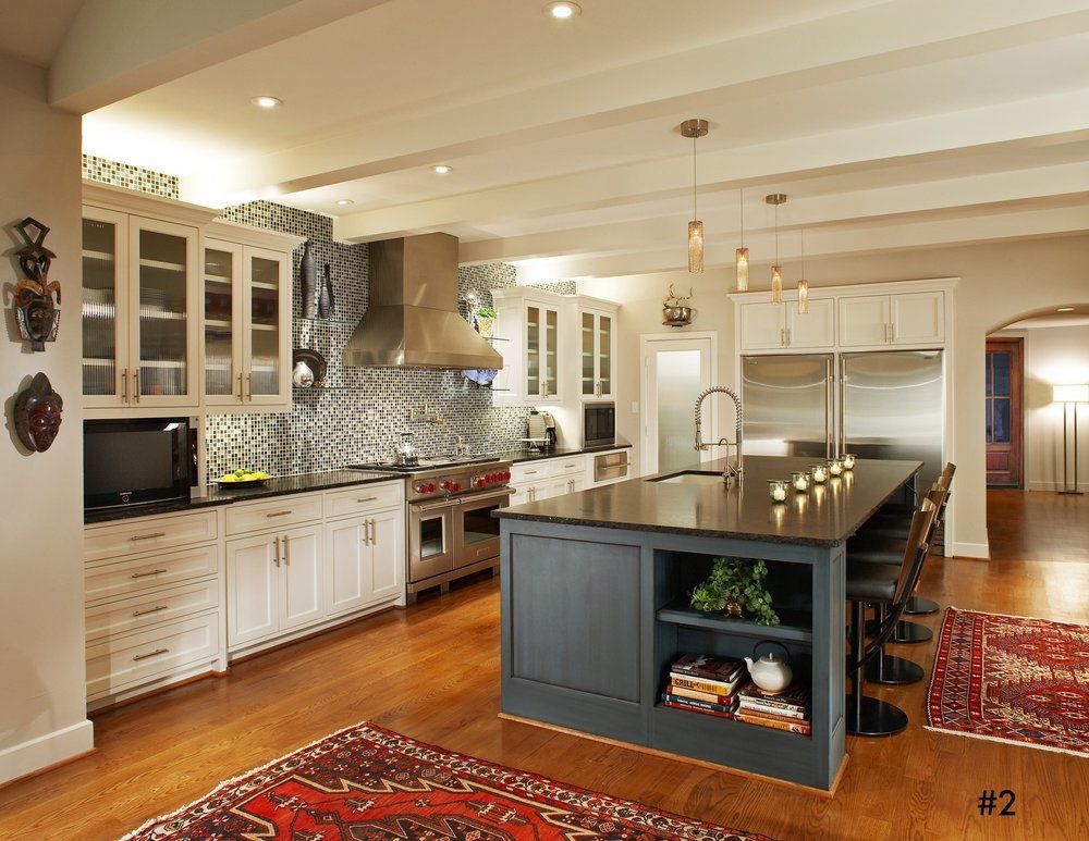 Elegant kitchen with island, white cabinetry, brick backsplash, wood floors, and Persian rugs.