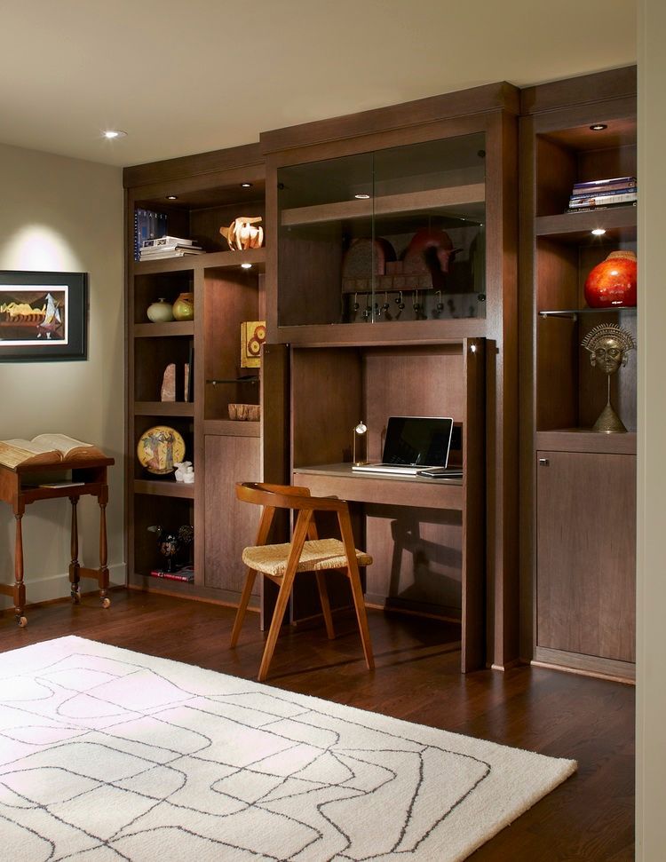 Built-in desk and bookshelves in a home office. Dark wood, with a chair and laptop. 
