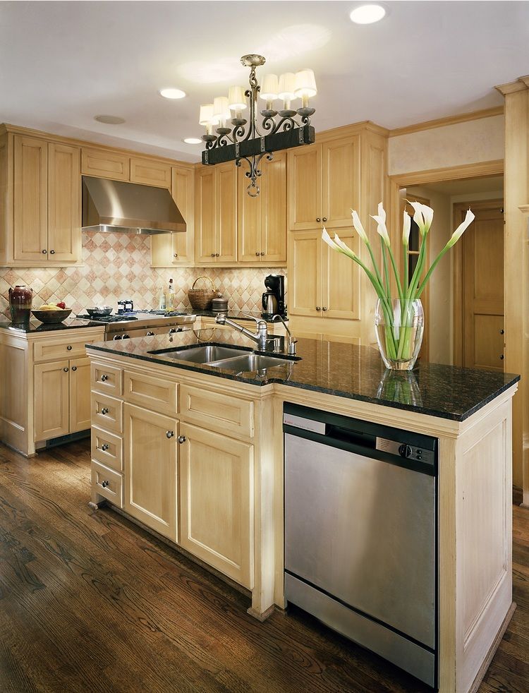 Kitchen with light wood cabinets, dark granite countertops, and stainless steel appliances.