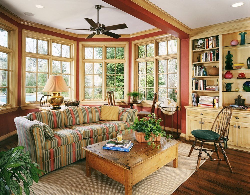 Cozy living room with corner windows, sofa, wooden coffee table, and built-in bookcase.