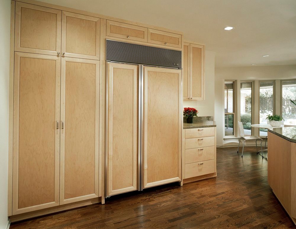 Light wood kitchen cabinets and refrigerator; hardwood floor.
