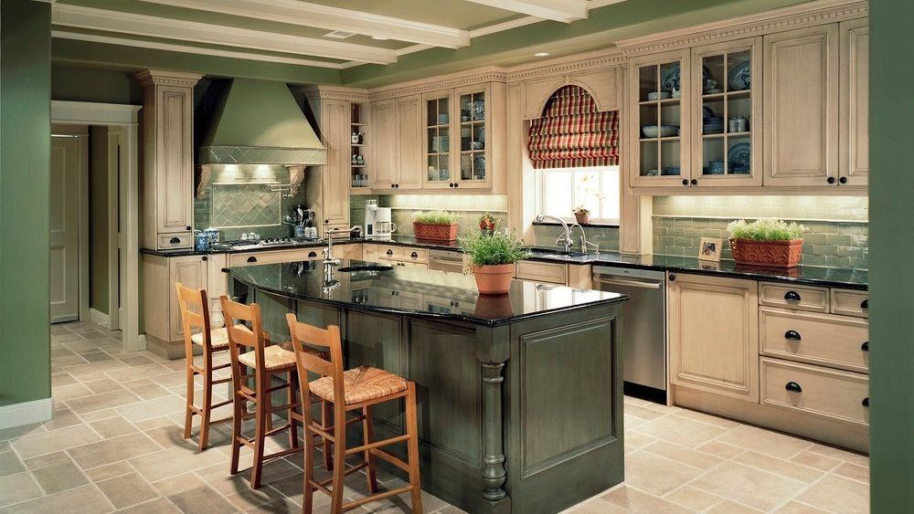 Kitchen with dark green island, light-colored cabinets, stainless steel appliances, and tile floor.