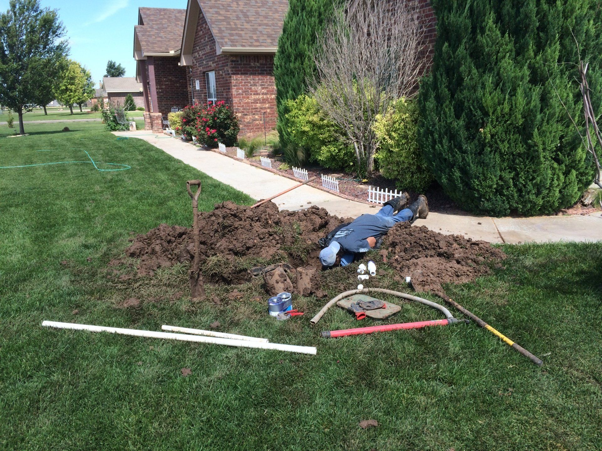 A man is laying in the dirt in front of a house.
