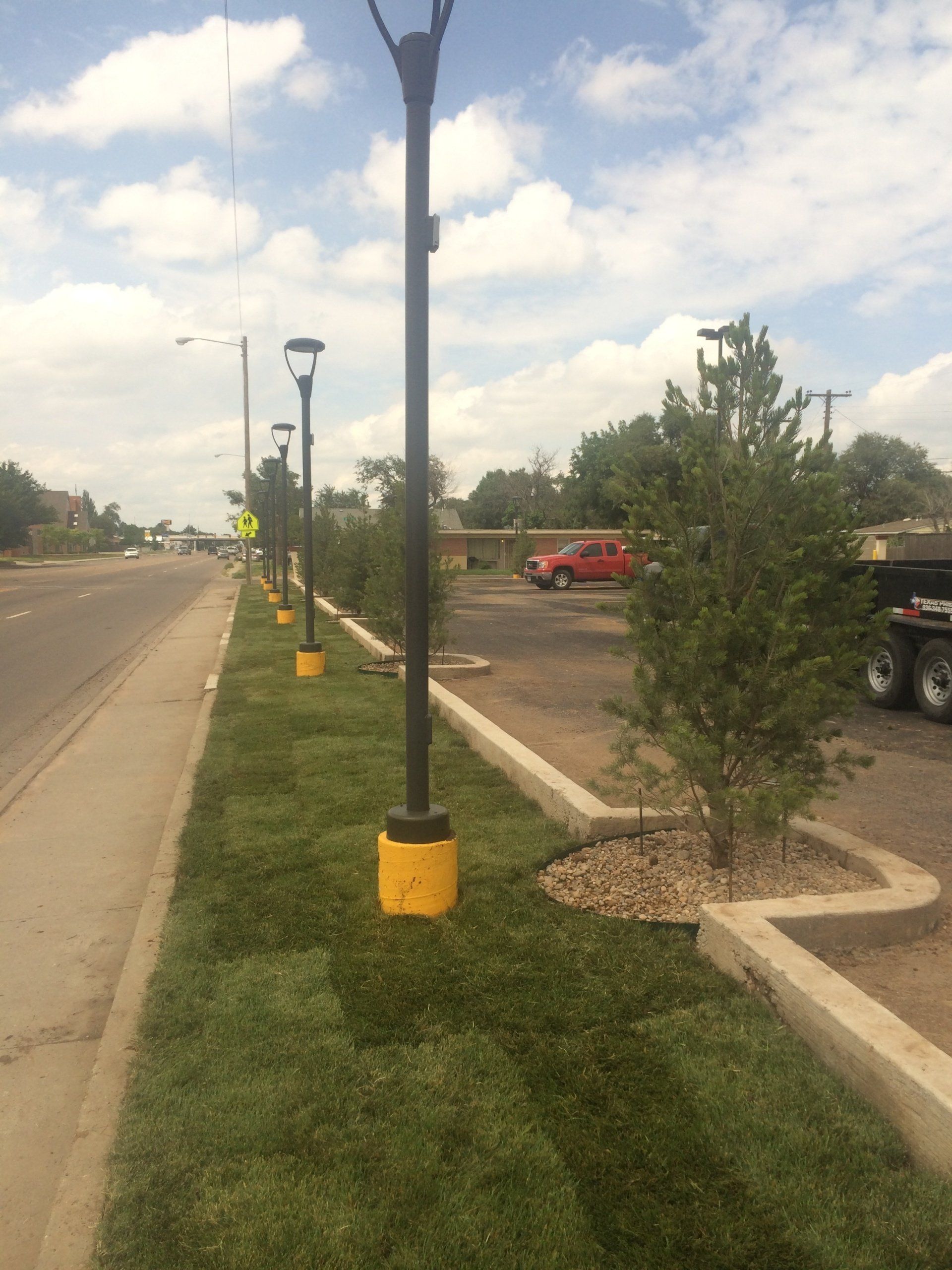 A row of street lights are lined up along the side of a road.
