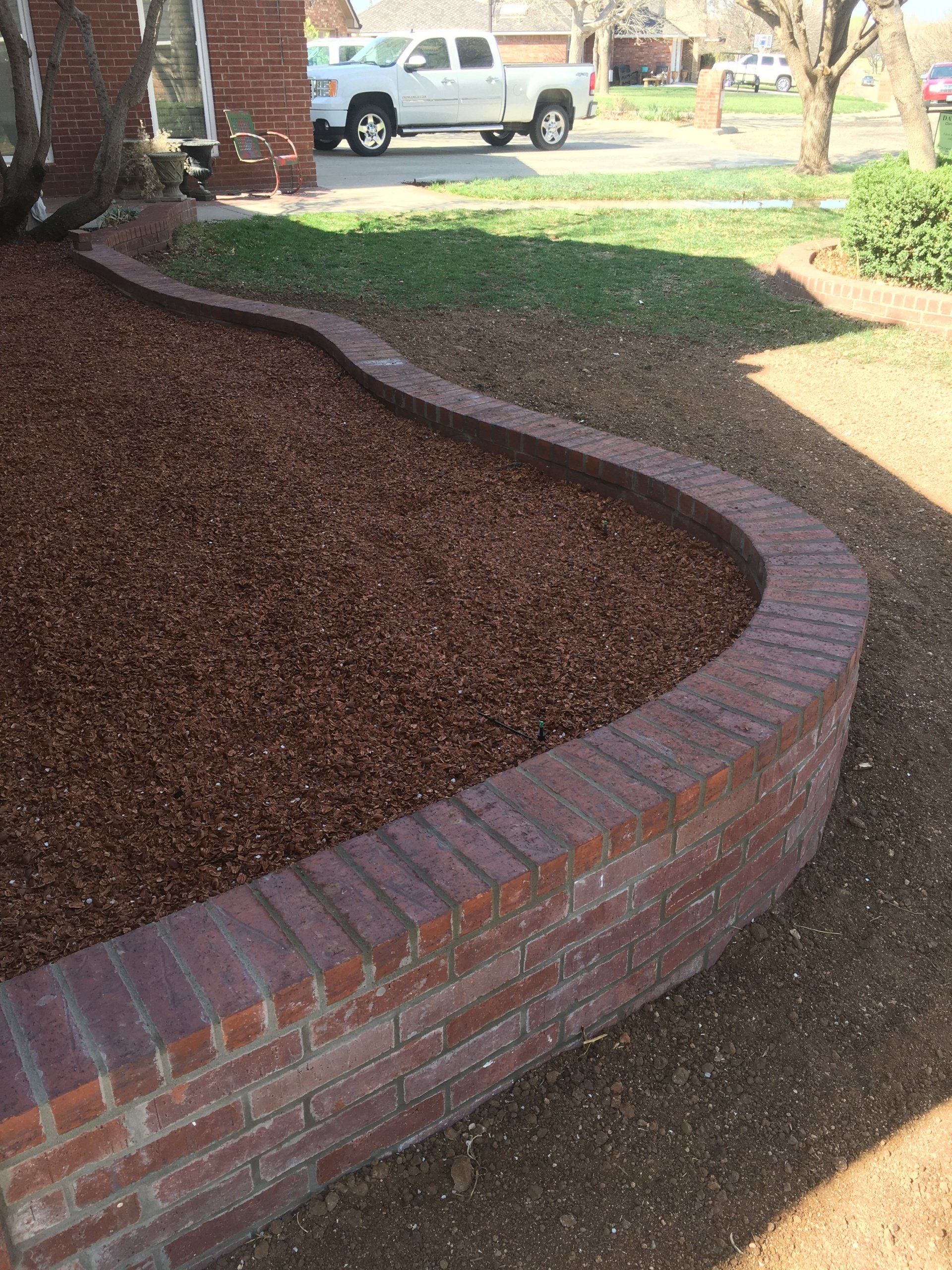 A white truck is parked in the driveway next to a brick wall.