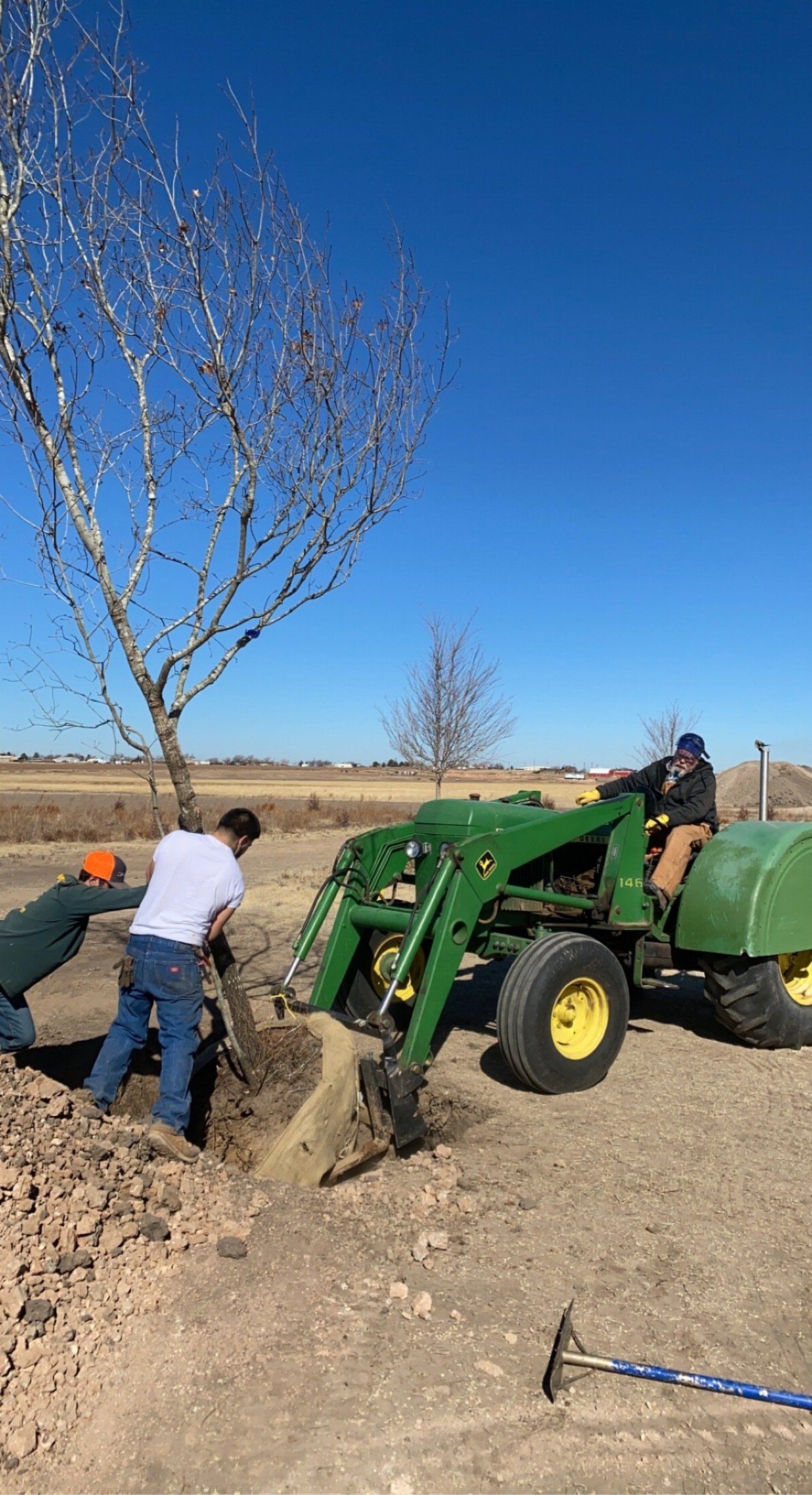 A man is riding a tractor to plant a tree.