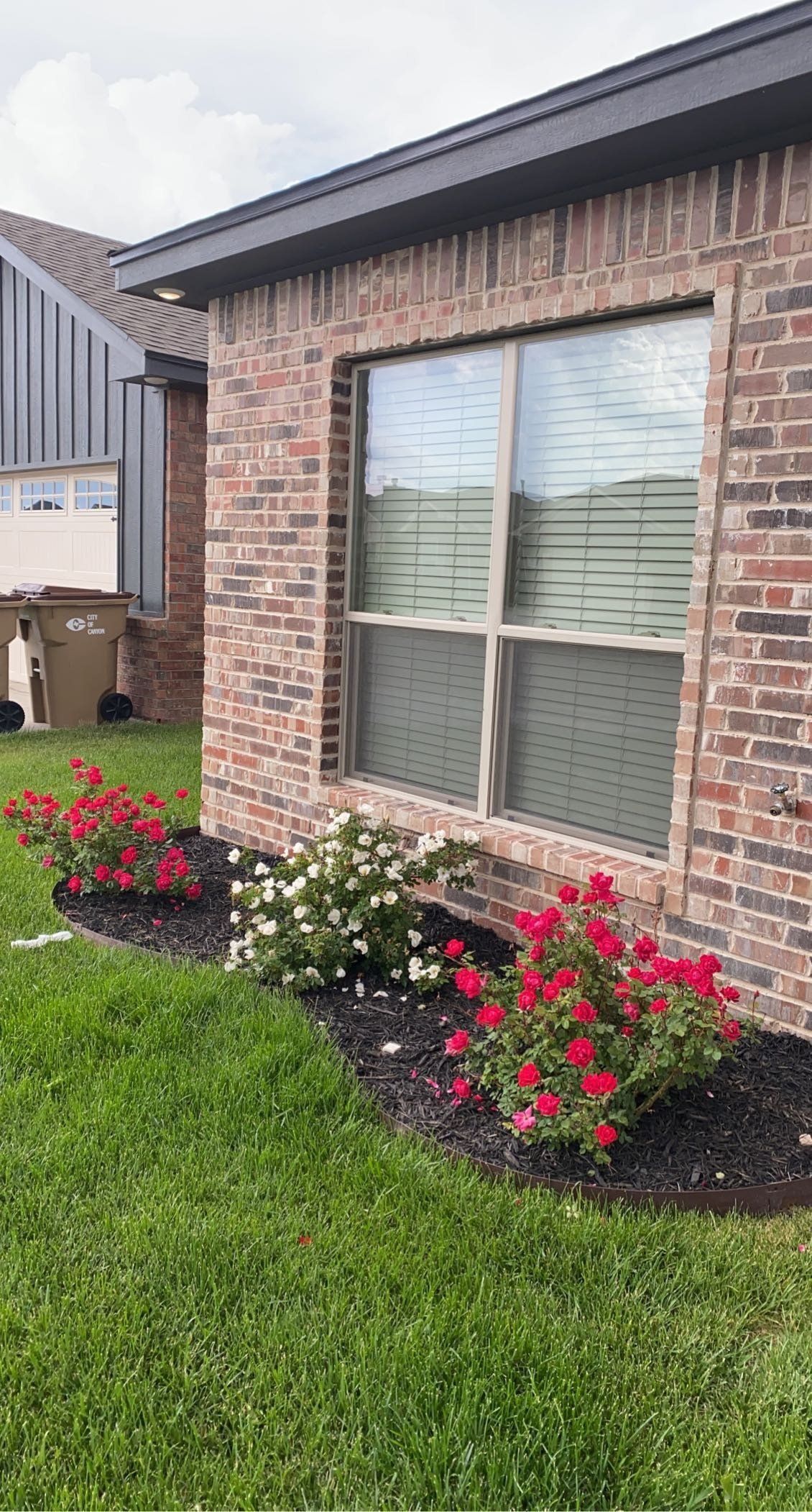 A brick house with a window and flowers in front of it.