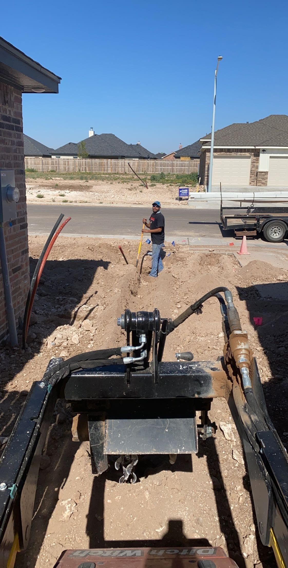 A man is digging a hole in the dirt in front of a house.