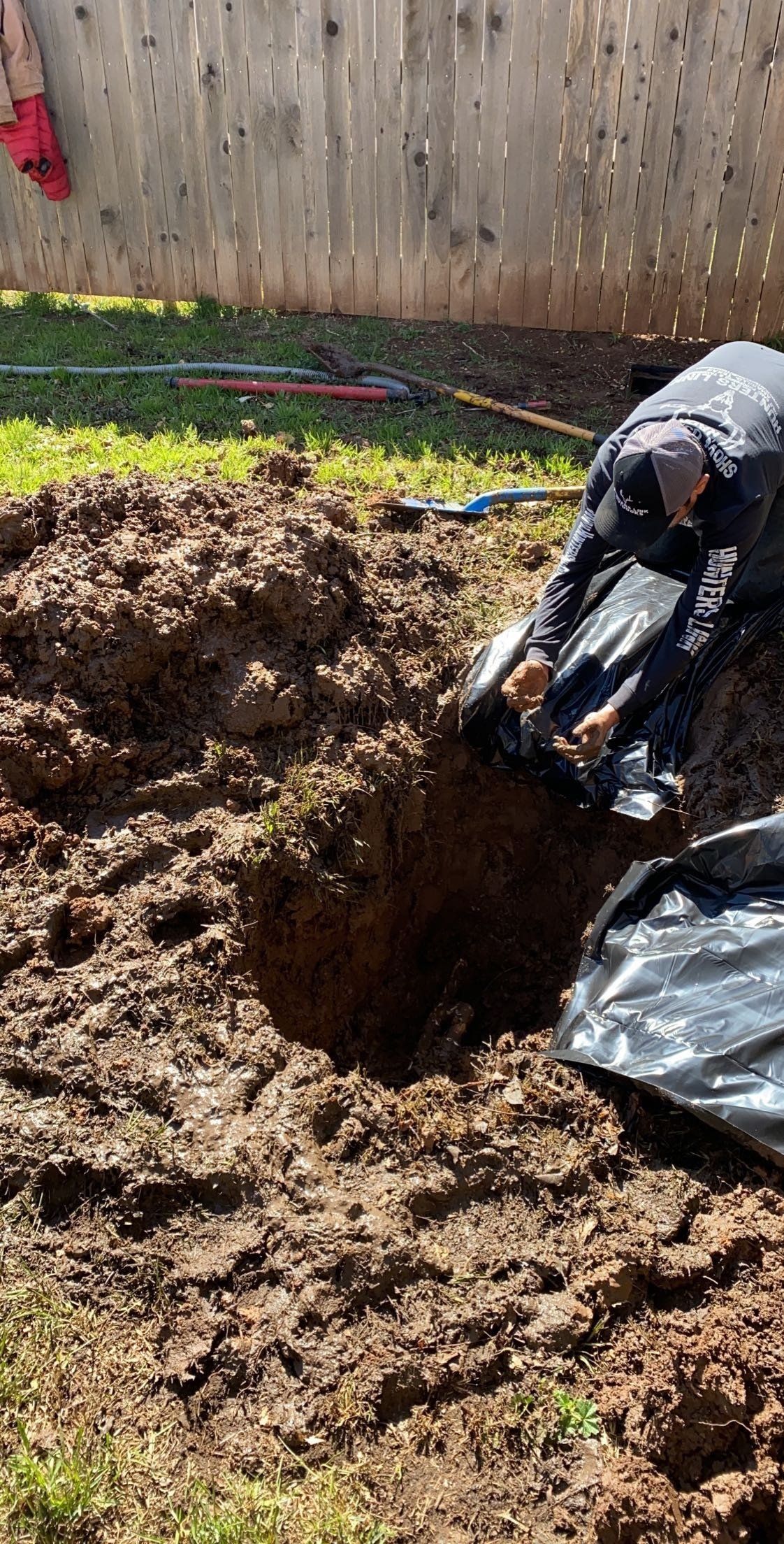 A man is digging a hole in the dirt in a yard.