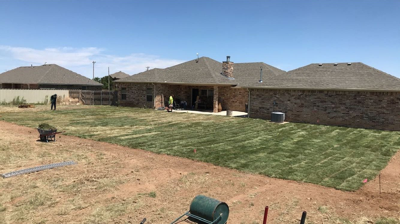 A large brick house with a lush green lawn in front of it.