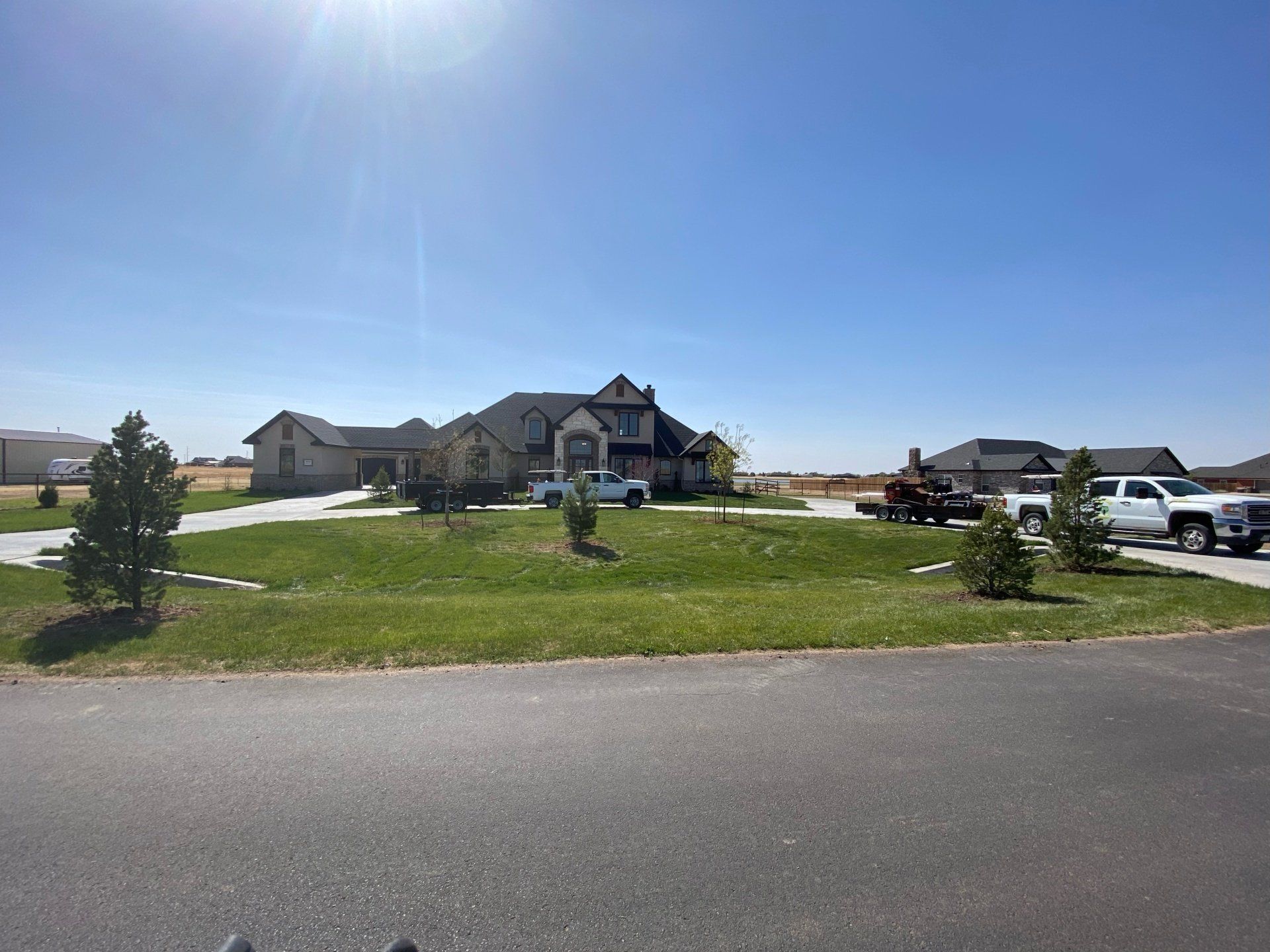 A large house is sitting on top of a lush green field next to a road.