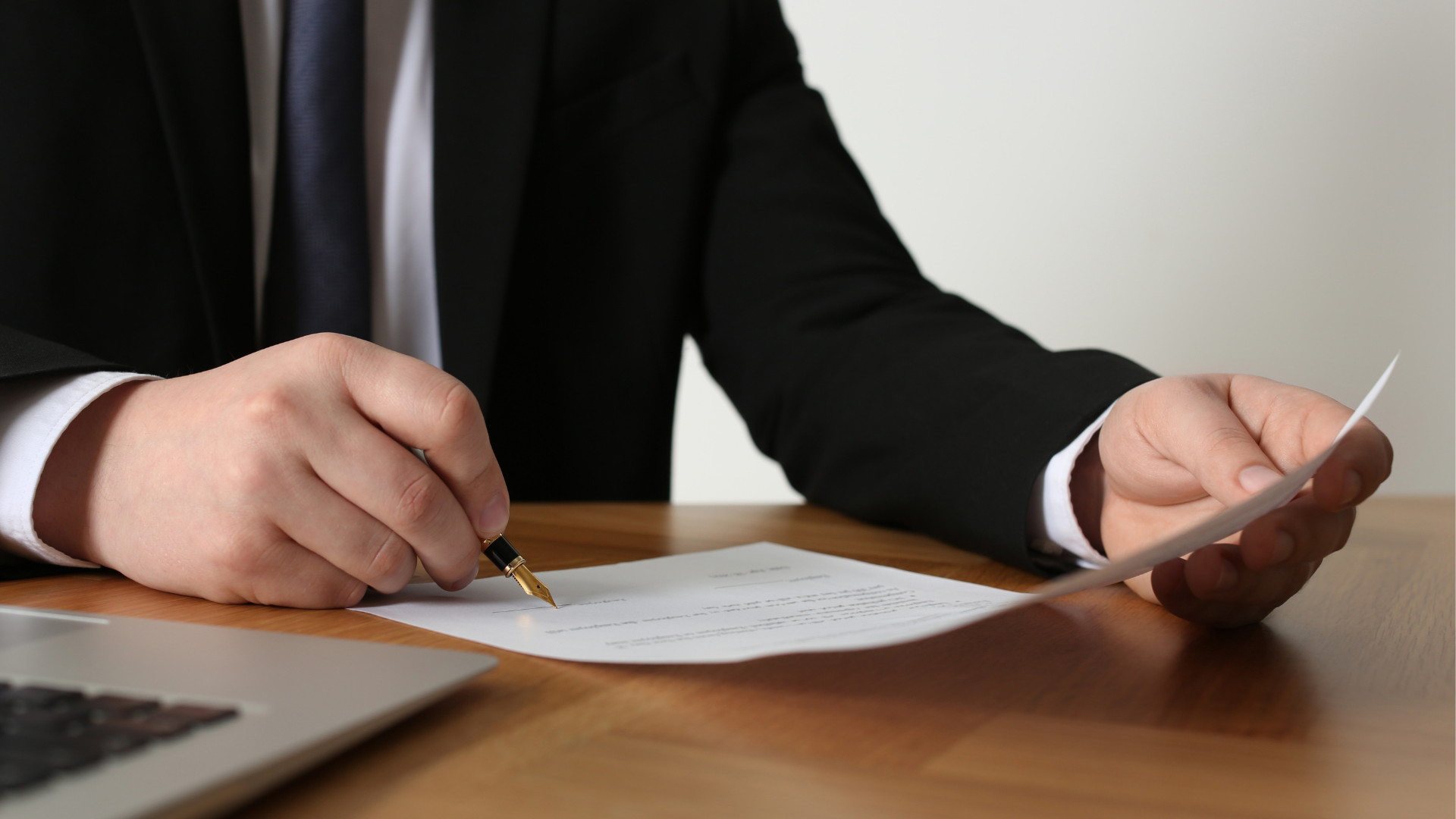 A man in a suit and tie is writing on a piece of paper.