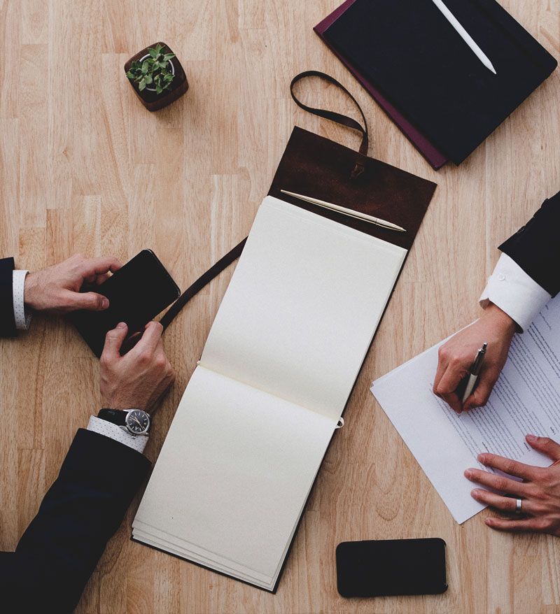two people are sitting at a table with papers and a notebook