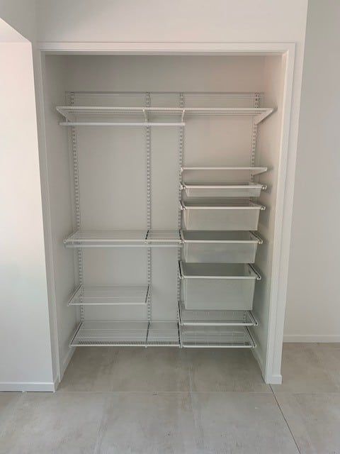 White closet organizer with shelves, rods, and pull-out drawers; empty, bright room— Ezyshelf in Manunda, QLD 