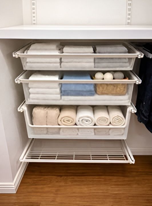 Shelves in a closet holding folded and rolled towels in white bins, neatly organized.— Ezyshelf in Manunda, QLD 