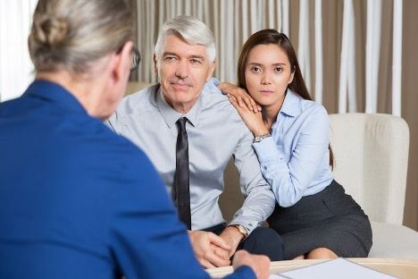 Two people in a meeting with a man in a blue suit, seated in a bright office