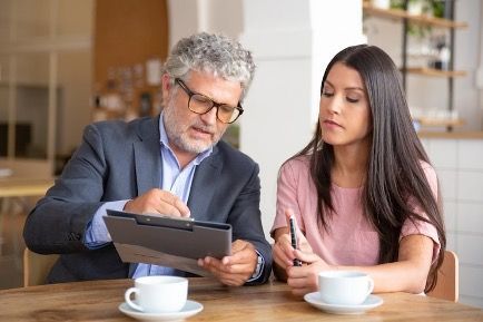 a man and woman sitting at a table, looking at documents