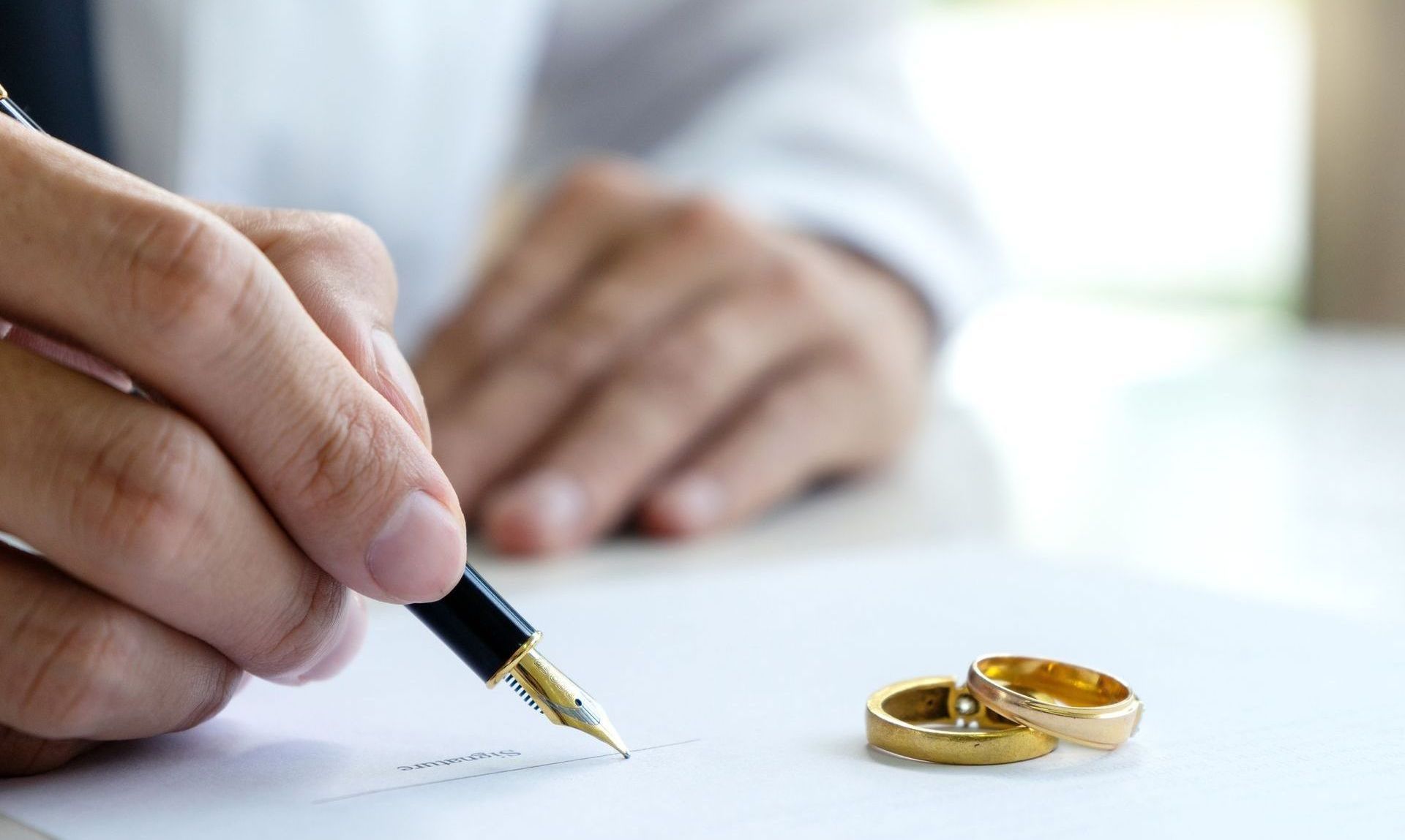 A man is writing on a piece of paper with a fountain pen.