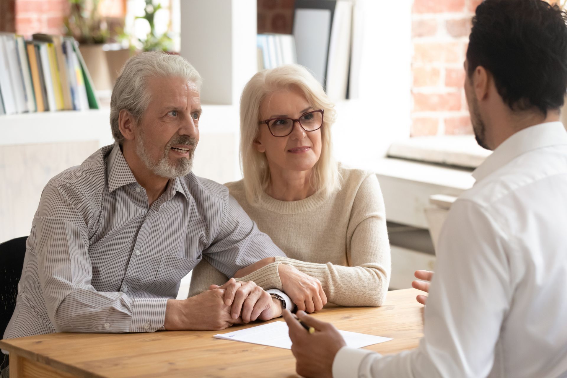 an elderly couple listening and sitting at a table
