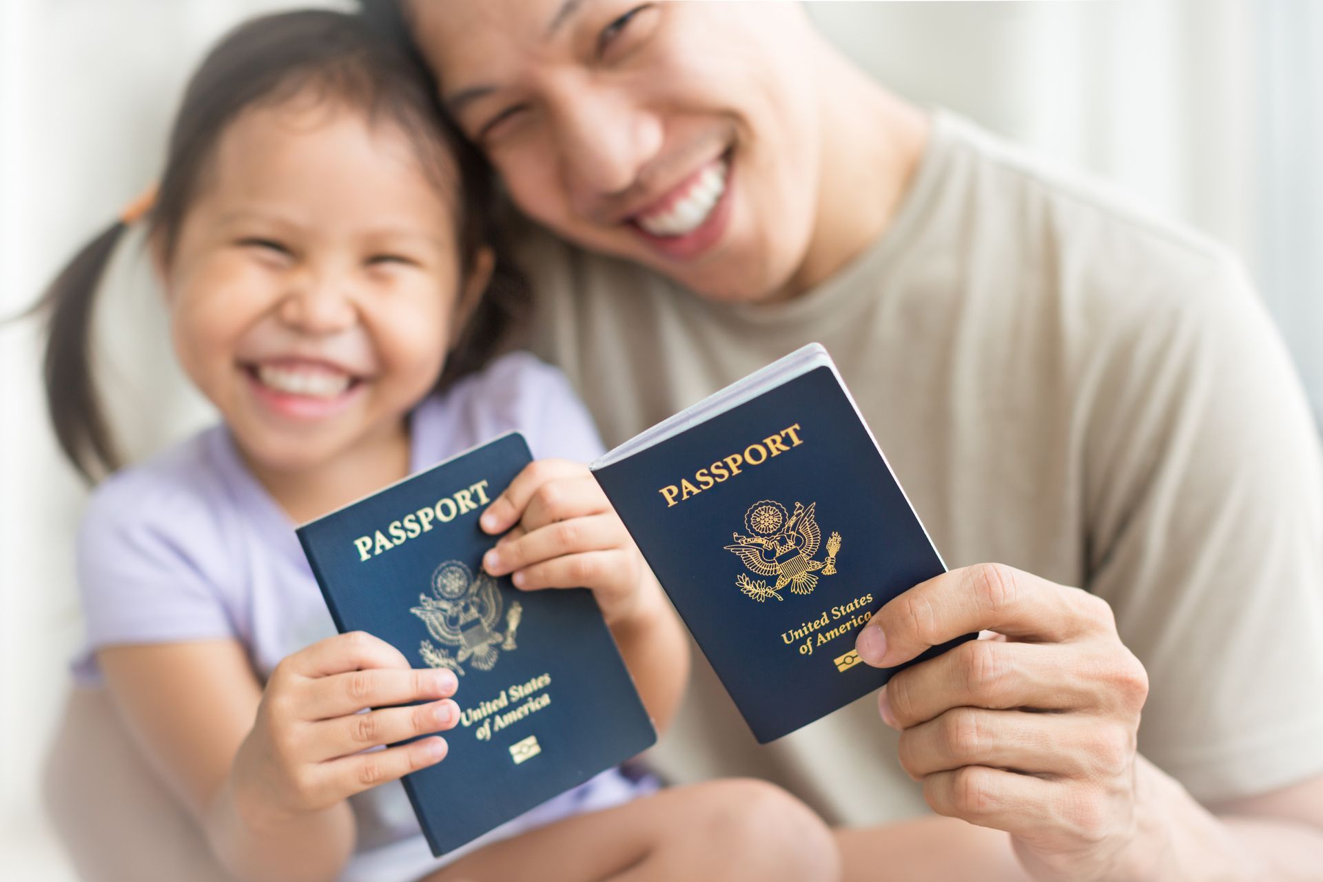 A man and a little girl are holding two passports.