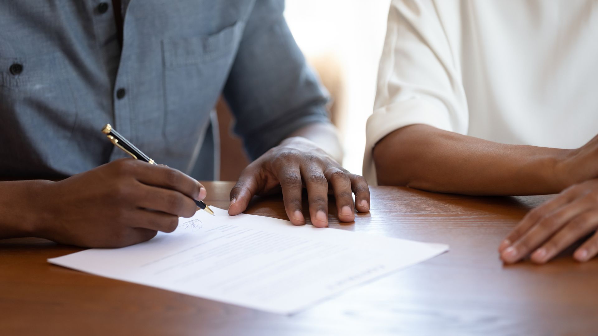 A man and a woman are sitting at a table signing a document.