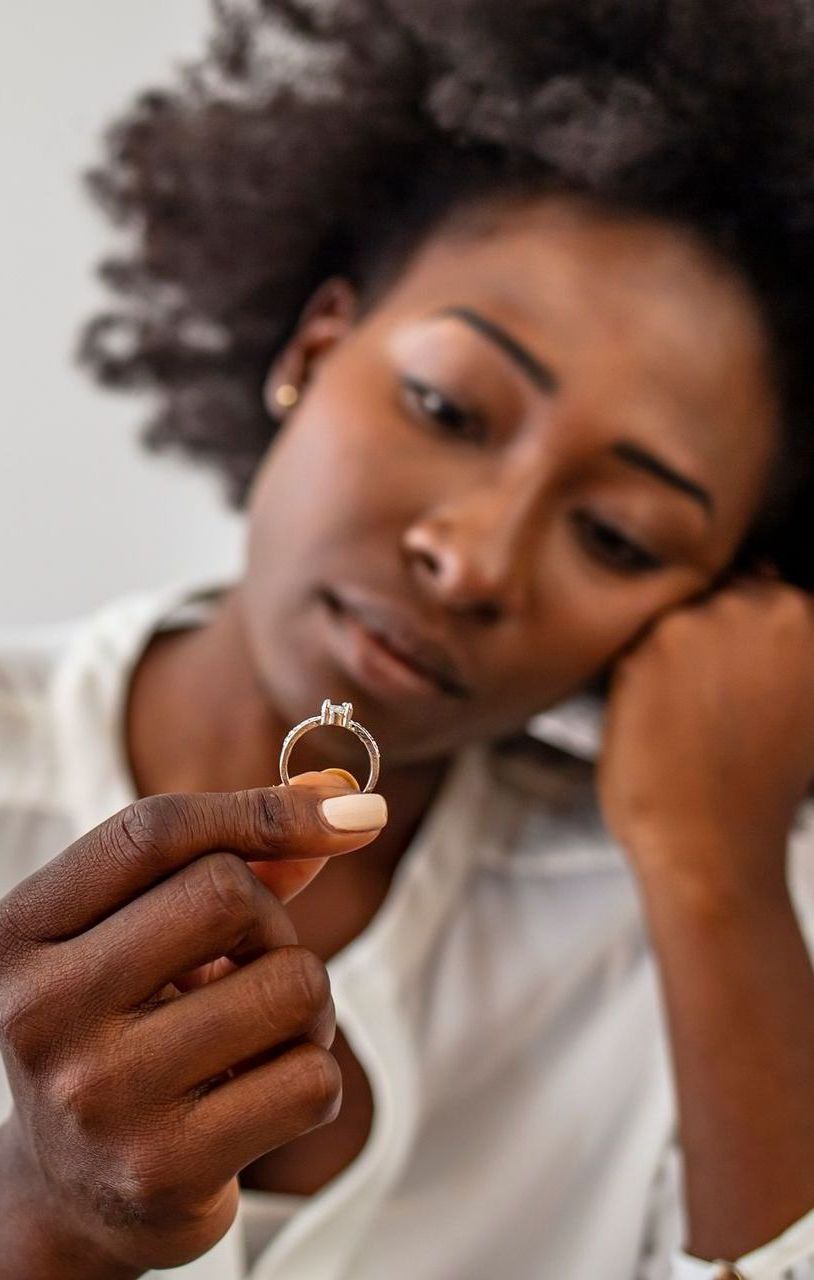 A woman is holding an engagement ring in her hand.