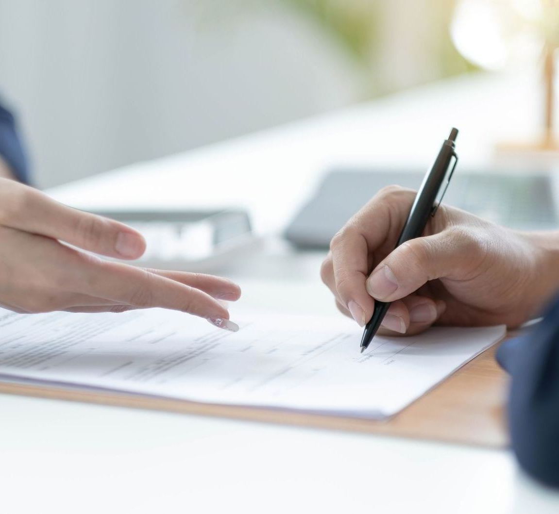 A person is writing on a piece of paper with a pen.